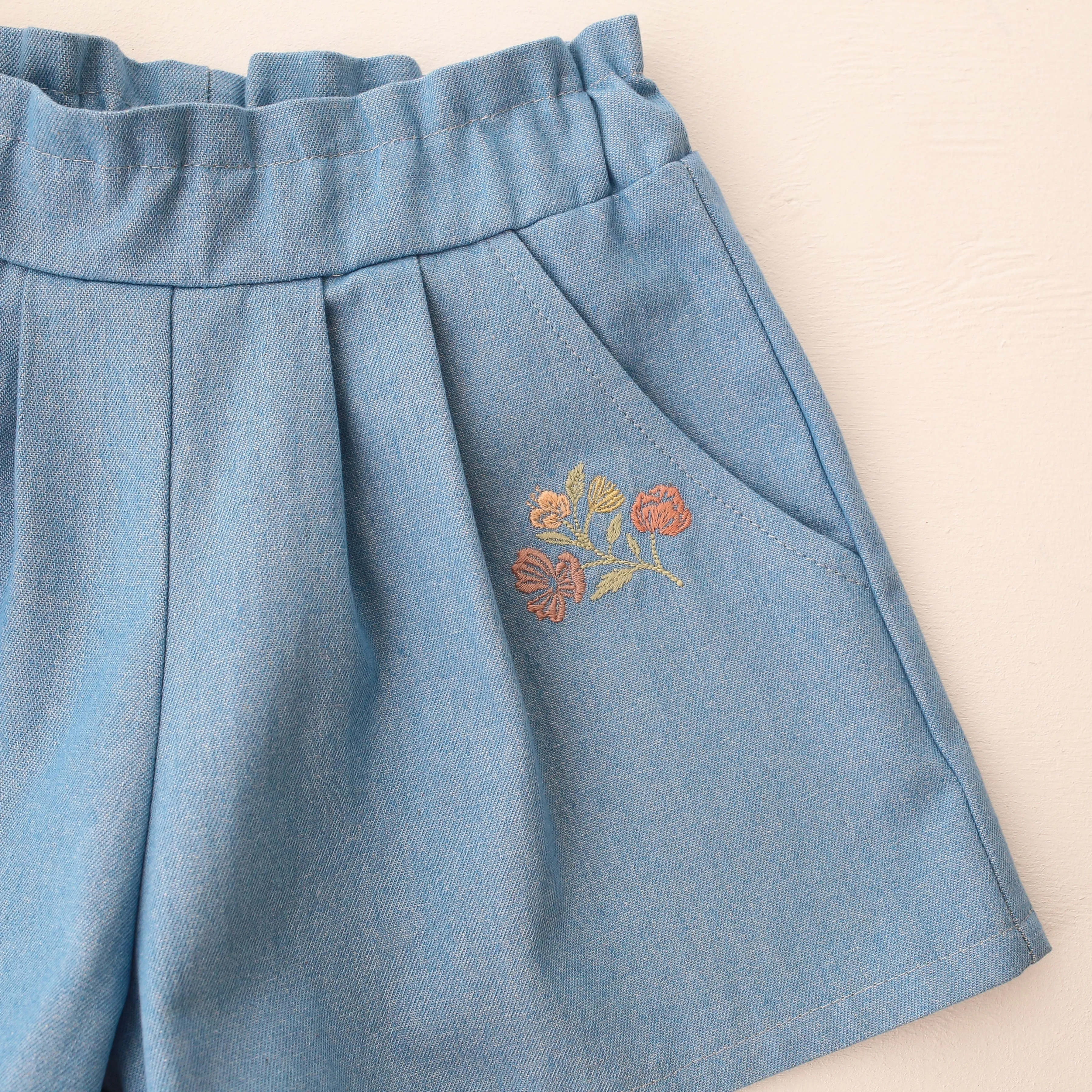 Light Blue Denim Paperbag Waist Shorts with "Wild Bells" Embroidery
